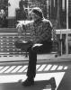 Gurney Norman sitting on a bench smiling